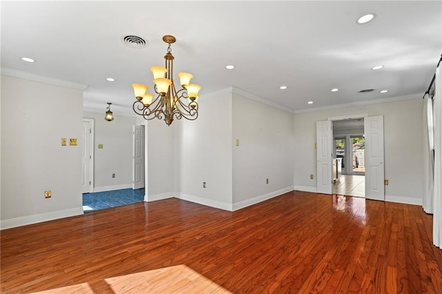 spare room featuring hardwood / wood-style floors, an inviting chandelier, and ornamental molding