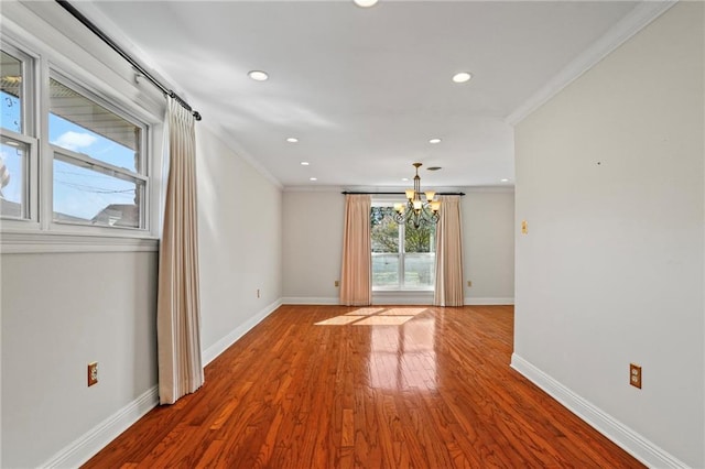 spare room featuring crown molding, hardwood / wood-style floors, and an inviting chandelier