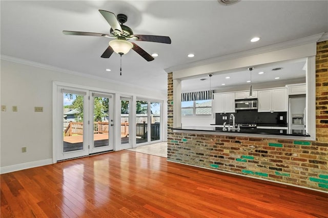 kitchen featuring white cabinets, crown molding, hanging light fixtures, light hardwood / wood-style floors, and stainless steel appliances