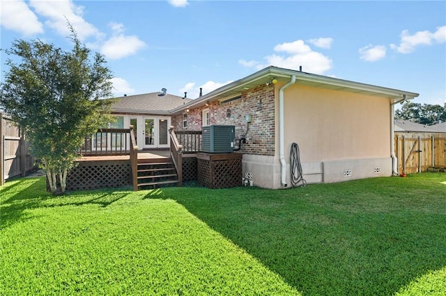 back of property featuring a lawn, cooling unit, and a wooden deck