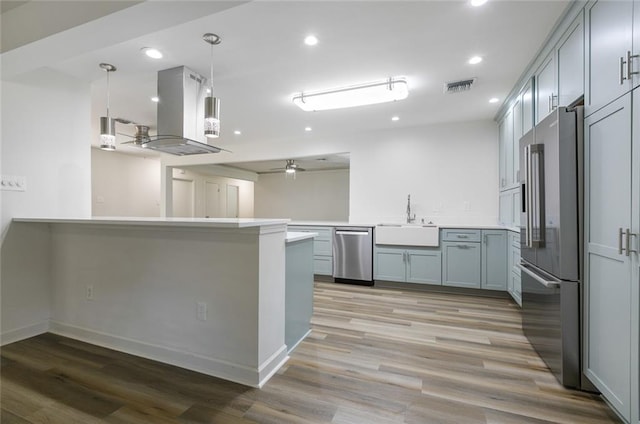 kitchen with sink, stainless steel appliances, light hardwood / wood-style flooring, kitchen peninsula, and island exhaust hood