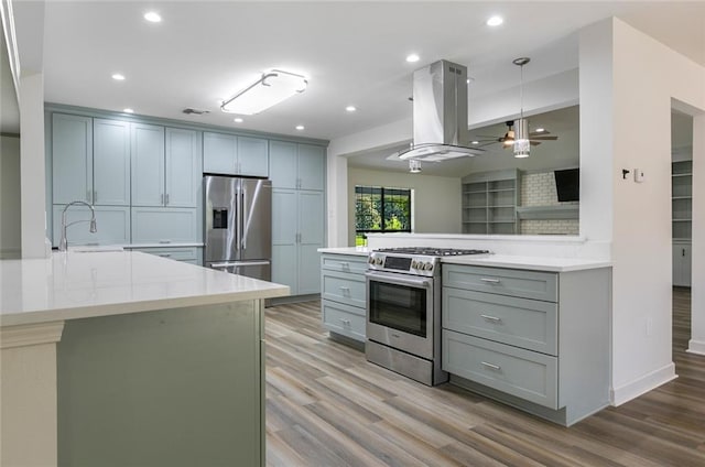 kitchen with sink, ceiling fan, kitchen peninsula, island exhaust hood, and stainless steel appliances