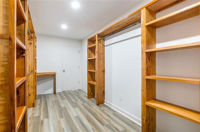 walk in closet with light hardwood / wood-style flooring