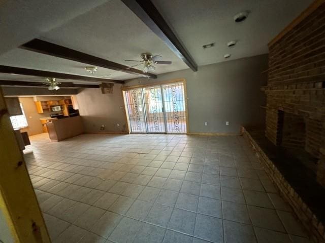 unfurnished living room with ceiling fan, beamed ceiling, light tile patterned floors, and a brick fireplace