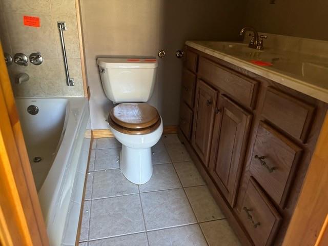 bathroom featuring tile patterned flooring, a bath, vanity, and toilet