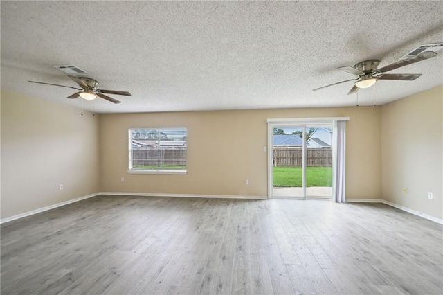 unfurnished room with wood-type flooring, a textured ceiling, and plenty of natural light