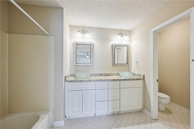 full bathroom featuring vanity, tile patterned floors, washtub / shower combination, toilet, and a textured ceiling