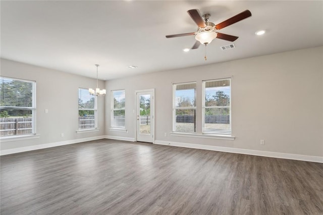 empty room featuring ceiling fan with notable chandelier and dark wood-type flooring