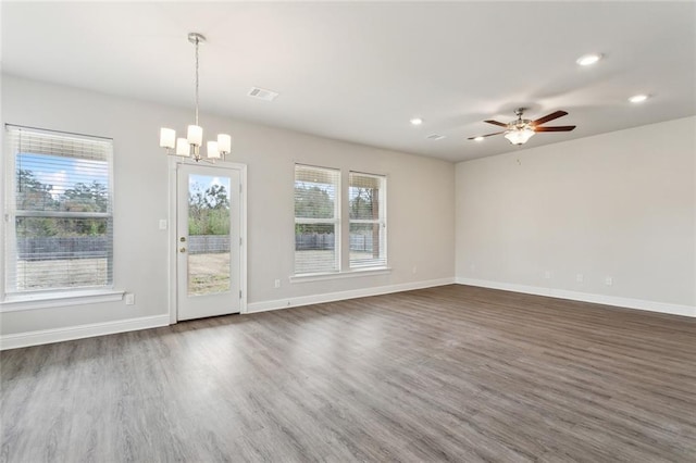 spare room with ceiling fan with notable chandelier and dark wood-type flooring