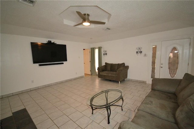 living room with ceiling fan, light tile patterned flooring, and a textured ceiling