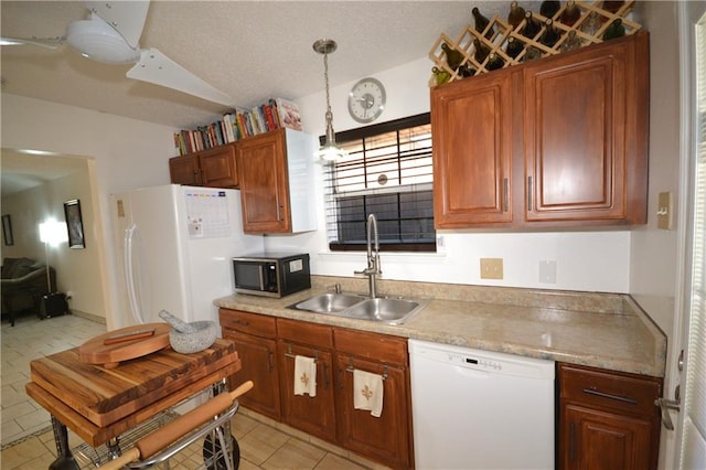 kitchen featuring light tile patterned floors, white appliances, hanging light fixtures, and sink