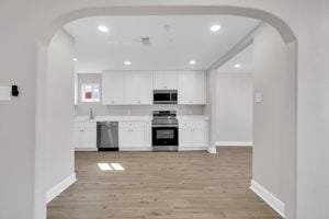 kitchen featuring white cabinets, stainless steel appliances, and light hardwood / wood-style floors