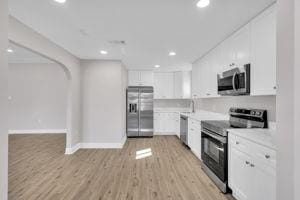 kitchen with white cabinets, stainless steel appliances, and light wood-type flooring