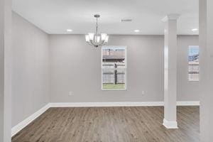 unfurnished dining area featuring hardwood / wood-style flooring and an inviting chandelier