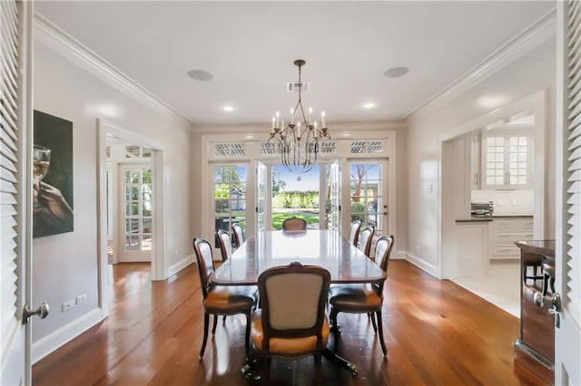 dining space featuring hardwood / wood-style floors, ornamental molding, and an inviting chandelier