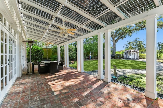 view of patio / terrace with ceiling fan, a storage shed, and french doors