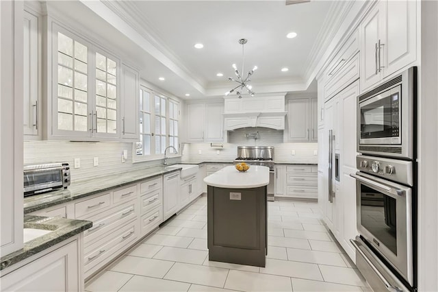 kitchen featuring a center island, sink, decorative light fixtures, white cabinetry, and stainless steel appliances