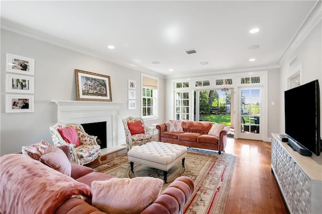 living room with wood-type flooring, ornamental molding, and a wealth of natural light