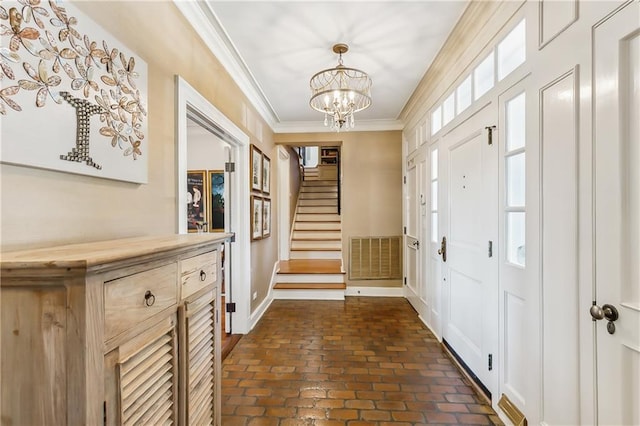 foyer entrance with a notable chandelier and ornamental molding