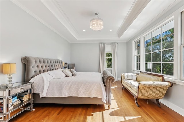 bedroom with a tray ceiling, multiple windows, and light hardwood / wood-style flooring