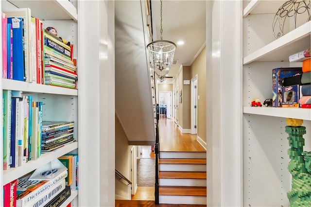 stairs featuring hardwood / wood-style floors and an inviting chandelier