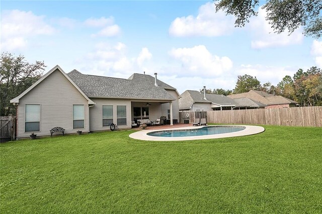 back of house featuring a lawn, ceiling fan, a fenced in pool, and a patio