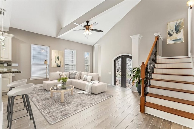 living room featuring ceiling fan, french doors, light wood-type flooring, high vaulted ceiling, and stairs