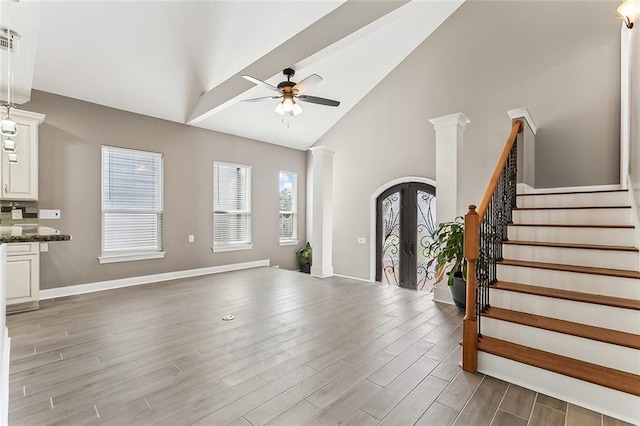 interior space featuring ceiling fan, high vaulted ceiling, stairway, french doors, and light wood-style flooring