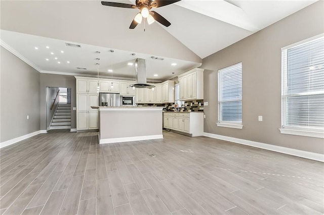kitchen with stainless steel fridge, open floor plan, ceiling fan, and island range hood