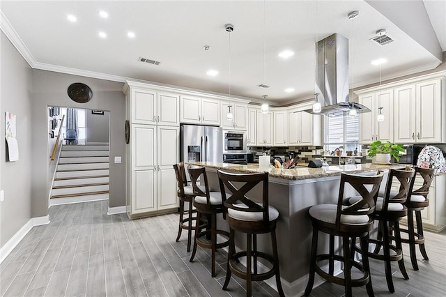 kitchen featuring light stone countertops, island range hood, stainless steel appliances, visible vents, and a center island