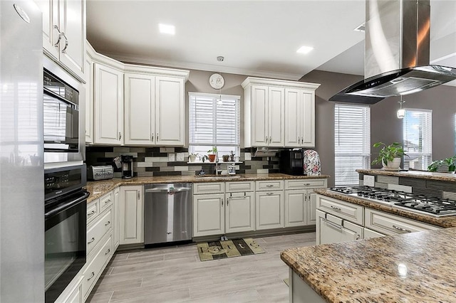 kitchen with stainless steel appliances, backsplash, white cabinets, and island range hood