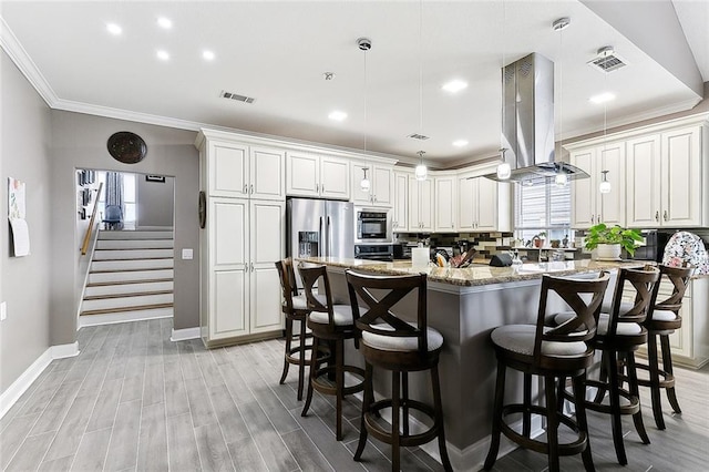 kitchen featuring visible vents, crown molding, a center island, island range hood, and stainless steel appliances