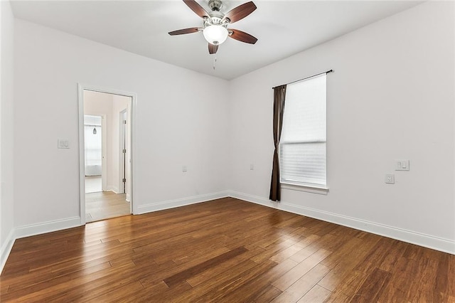 unfurnished room featuring dark wood-style floors, ceiling fan, and baseboards