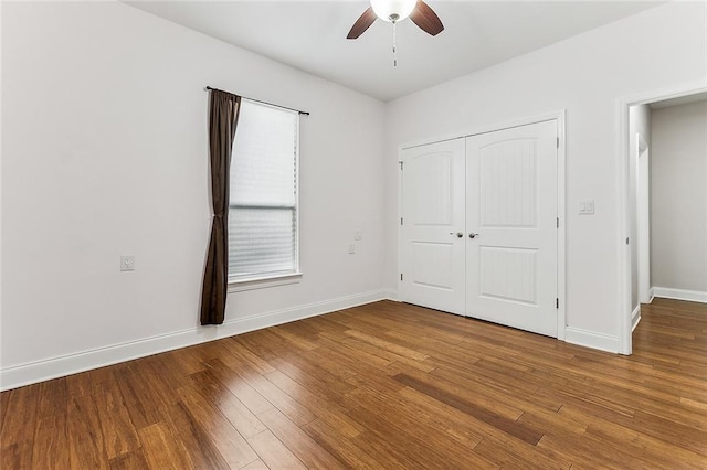 unfurnished bedroom featuring baseboards, a ceiling fan, wood finished floors, and a closet
