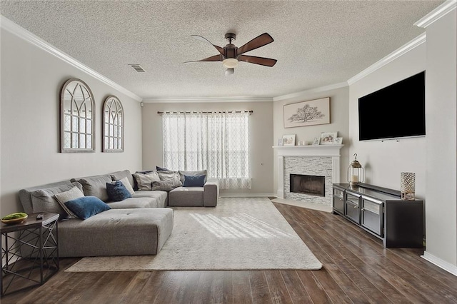 living room with ceiling fan, dark hardwood / wood-style flooring, a textured ceiling, a fireplace, and ornamental molding