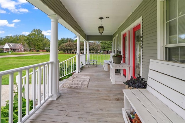 wooden deck featuring a porch and a lawn