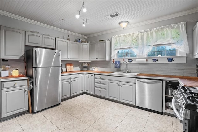 kitchen featuring backsplash, gray cabinetry, stainless steel appliances, crown molding, and sink