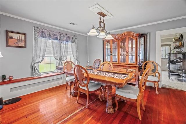 dining room with hardwood / wood-style floors, ornamental molding, and a chandelier