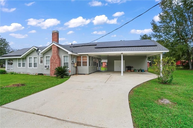 ranch-style home featuring a carport, a sunroom, solar panels, and a front lawn