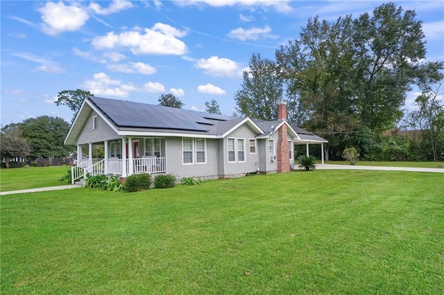 ranch-style house featuring a front lawn, covered porch, and solar panels