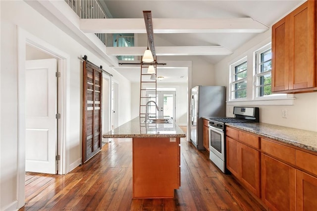 kitchen with a center island with sink, sink, vaulted ceiling with beams, a barn door, and stainless steel appliances