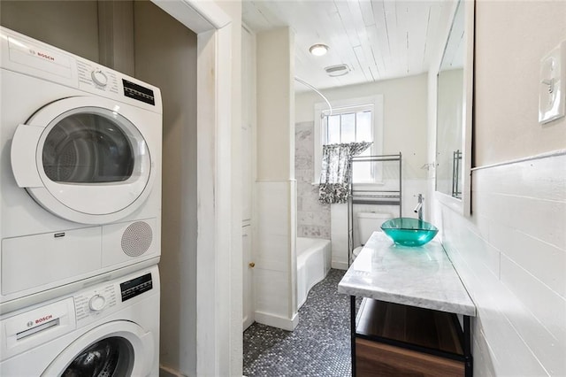 clothes washing area with stacked washer / dryer and sink