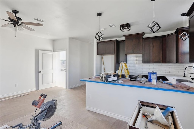 kitchen featuring kitchen peninsula, tasteful backsplash, ceiling fan, decorative light fixtures, and light hardwood / wood-style floors