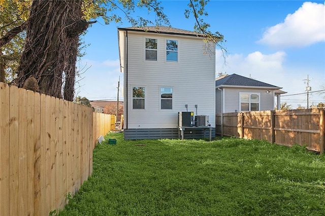 rear view of house featuring a yard and central AC unit