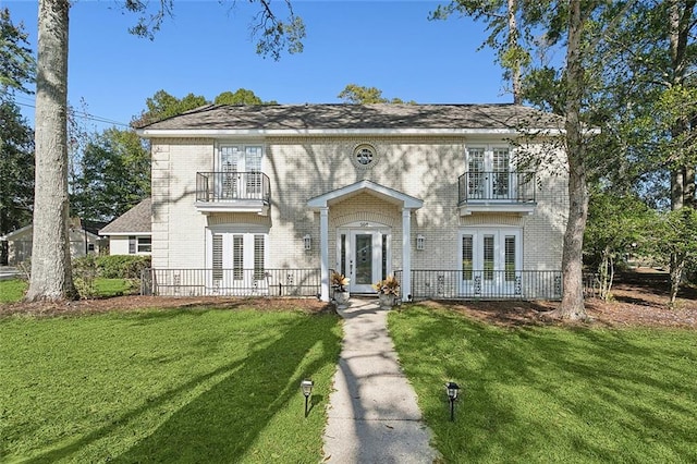 view of front of property with a balcony, a front lawn, and french doors