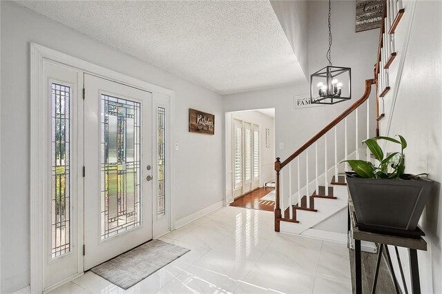 tiled foyer entrance with an inviting chandelier and a textured ceiling