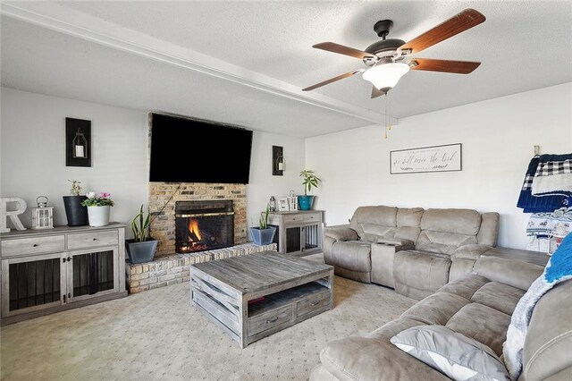 living room featuring a textured ceiling, beamed ceiling, ceiling fan, a brick fireplace, and light colored carpet