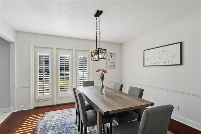 dining area with a textured ceiling and dark hardwood / wood-style flooring