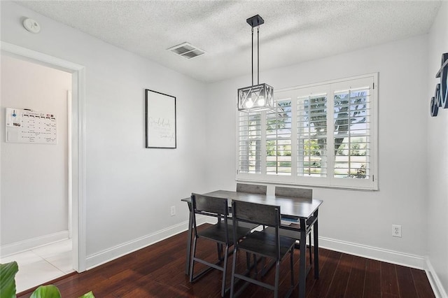 dining space with wood-type flooring and a textured ceiling