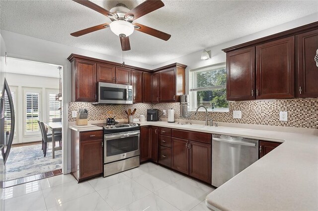 kitchen featuring a textured ceiling, appliances with stainless steel finishes, decorative backsplash, sink, and ceiling fan